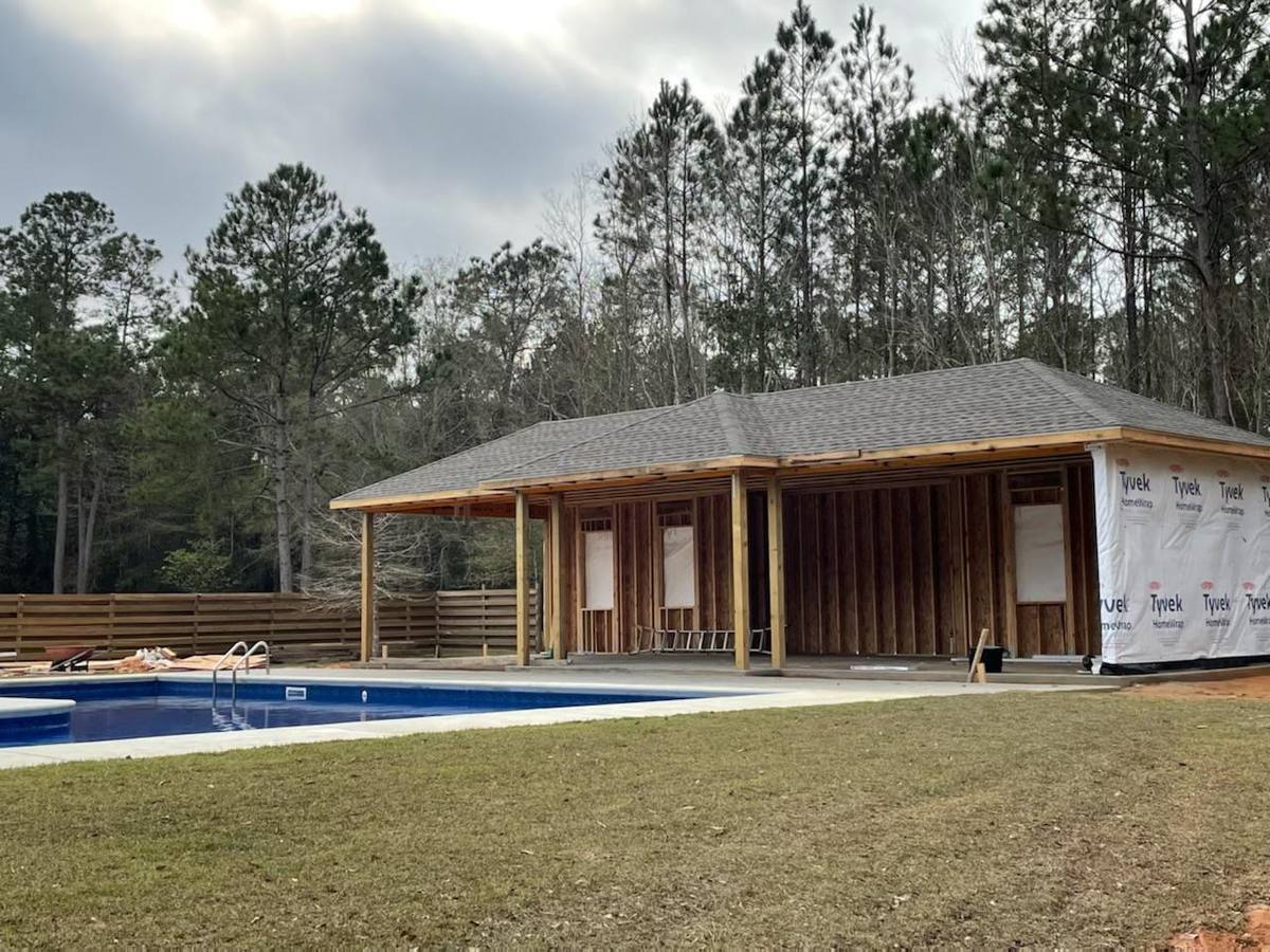 Covered pool pavilion under construction with shingled roof